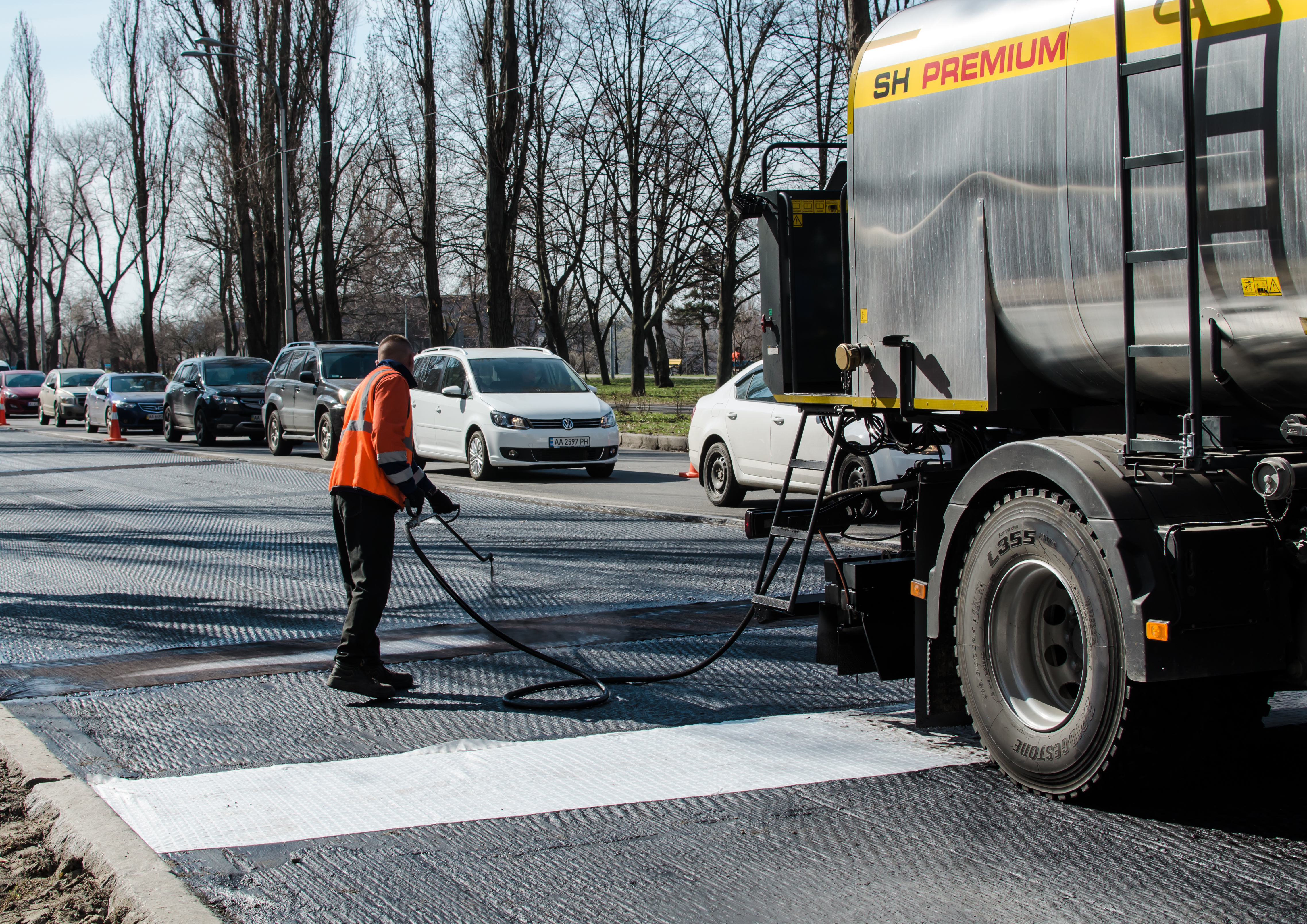 worker spraying asphalt sealant on a new road.