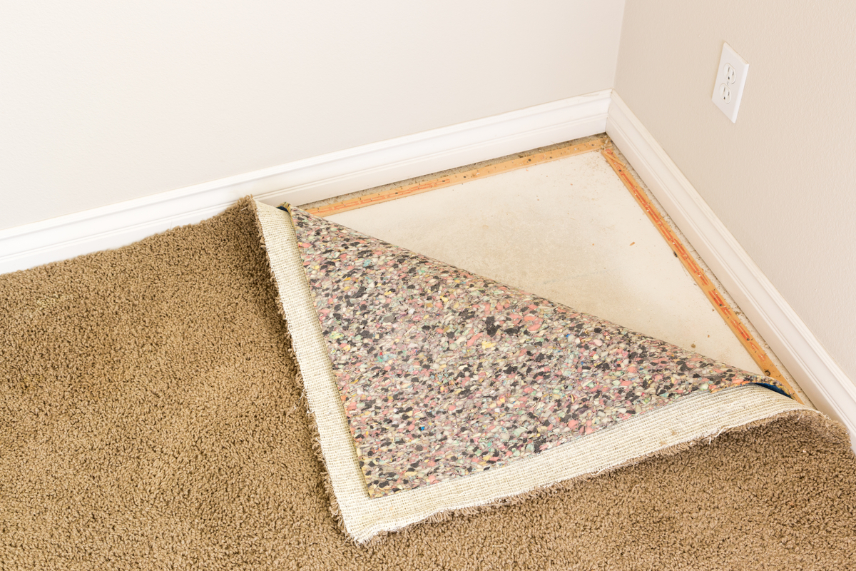 image of corner of carpet pulled back to review the padded underlayer