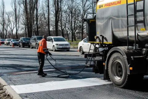 Person spreading asphalt emulsion on a road