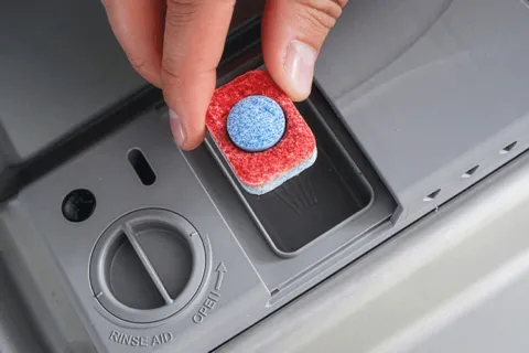 Detergent tablet being dropped in to dishwasher