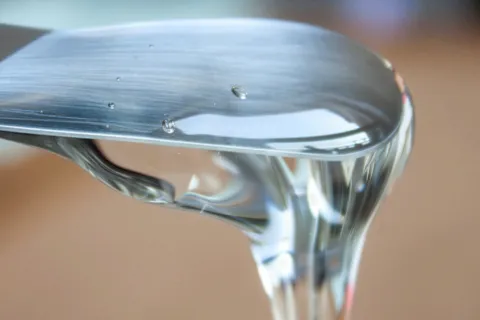 Clear glucose syrup flowing off a metal spatula