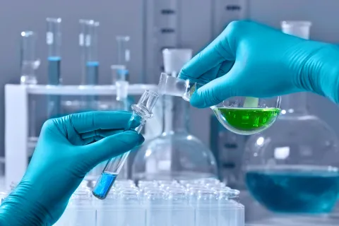 Liquid being poured from beaker into test tube in a scientific lab