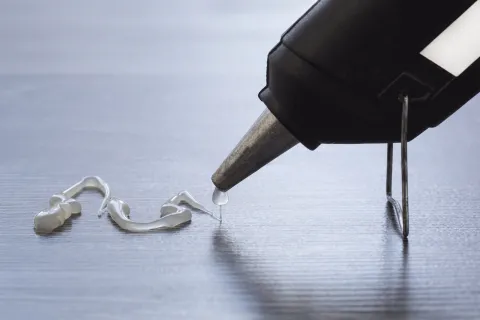 Hot glue gun expelling glue onto table