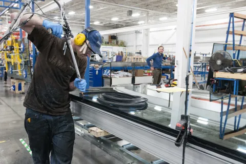 Man adding sealant to a window in an industrial environment