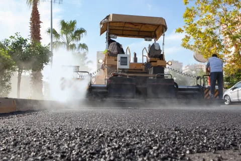 Rear view of asphalt paver laying down hot asphalt on a road