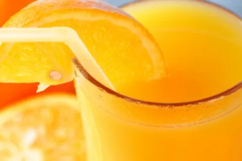 Glass of orange juice with orange slice and straw