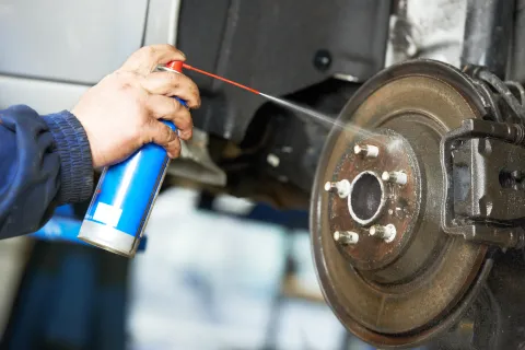 Mechanic spraying liquid solvent on a brake disc.
