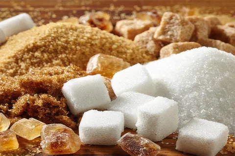Mounds of brown and white sugar crystals and white sugar cubes