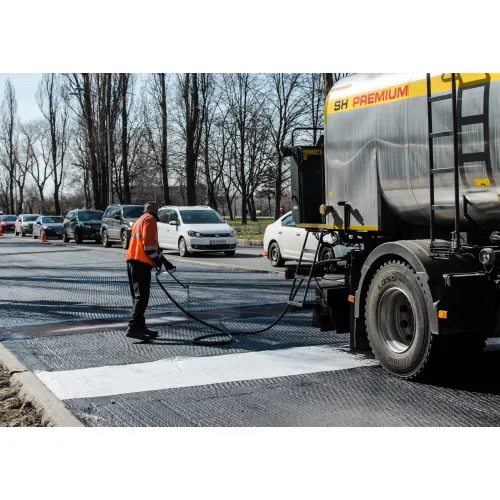 worker spraying asphalt sealant on a new road.